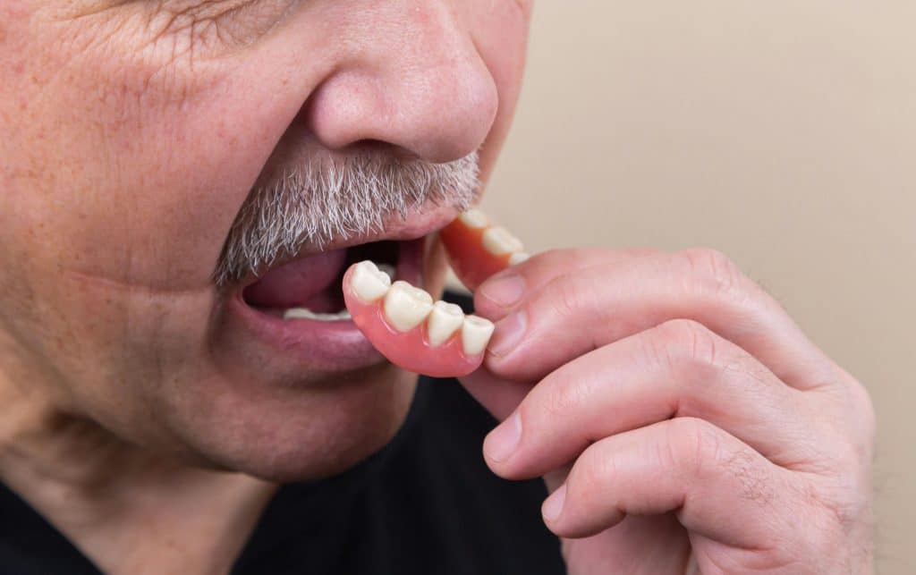Southbridge Dentistry - Dentures - Old man putting teeth in